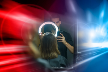Kritischer Kommentar zur Krise der Friseurbranche: Ein Friseur mit Ringlicht und Smartphone vor einem blau-roten Hintergrund, symbolisch für den Social-Media-Wahn im Salon.
