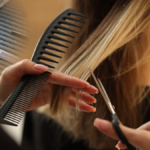 Nahaufnahme einer professionellen Friseurschere, die präzise eine Haarsträhne schneidet.