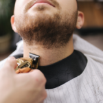 Nahaufnahme von der präzisen Rasur und dem Konturenschneiden eines Männerbartes im Salon.