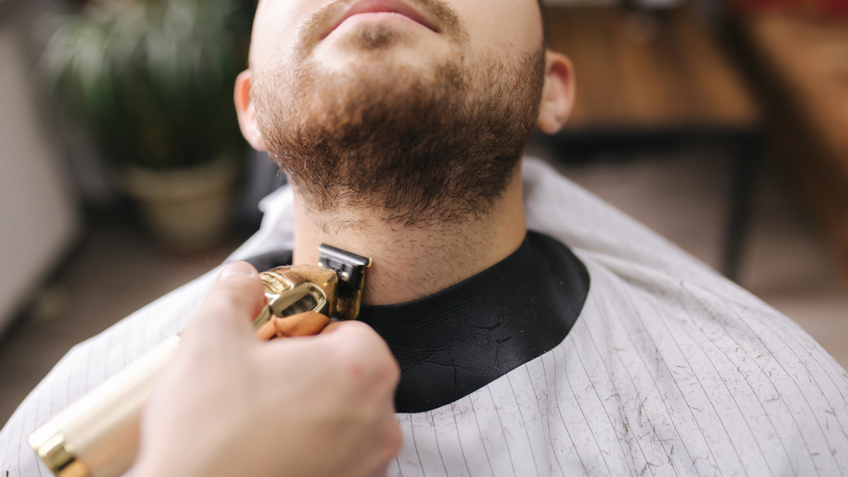 Nahaufnahme von der präzisen Rasur und dem Konturenschneiden eines Männerbartes im Salon.